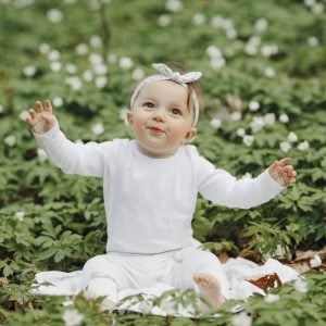 Beautiful little girl rejoices in the forest among the flowers